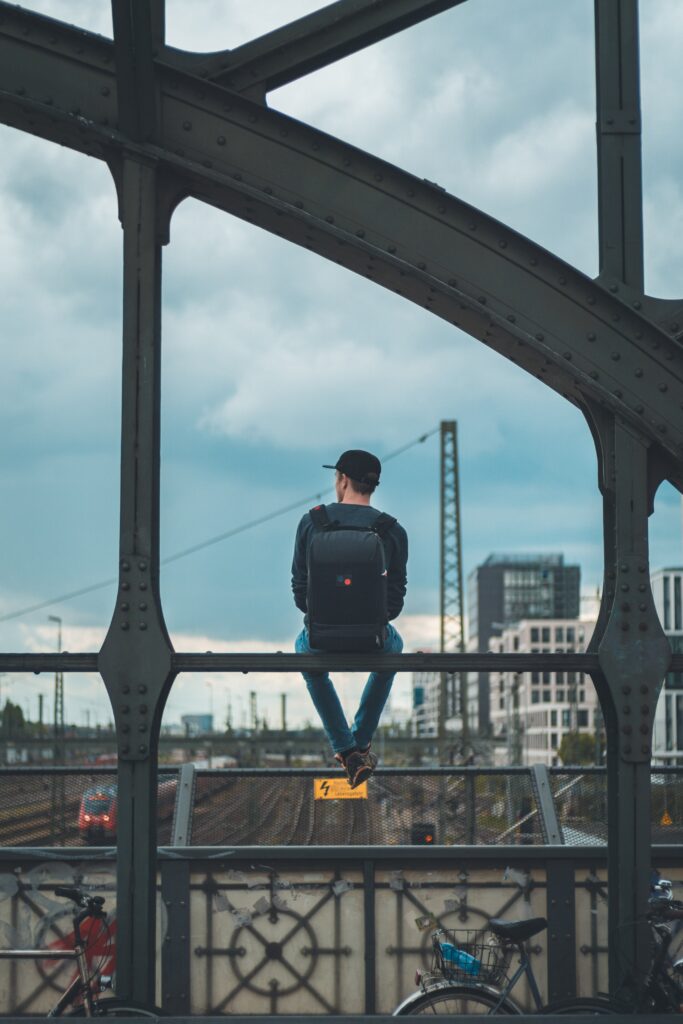 Traveler looking over the city from a bridge rail by shotinraww by Unsplash