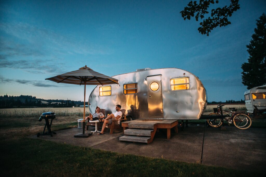 Two people hanging out in front of their RV at dusk, for the best travel trailer brands by Blake Wisz from Unsplash
